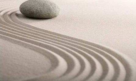 Une pierre repose sur le sable avec un motif de vagues. La question "Pourquoi rêver de sable en islam ?" est posée